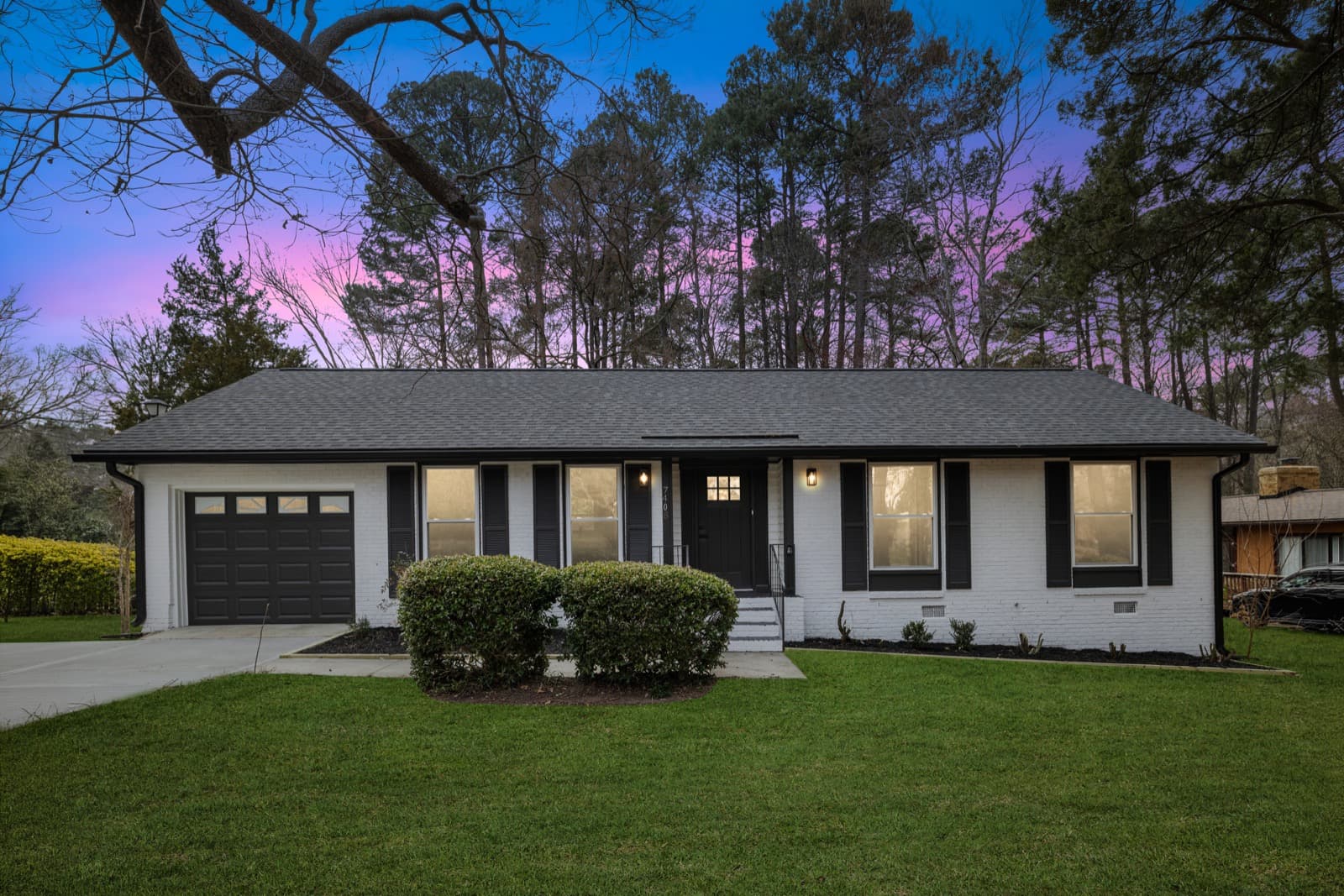 A North Carolina home Atlantis Homebuyers bought and renovated, white-brick exterior with black trim at dusk